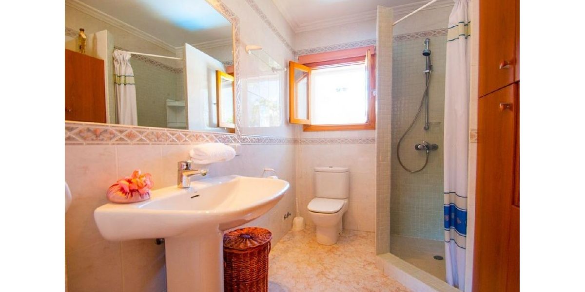 Cuarto de baño familiar de la vivienda también con ducha, lavabo y espejo.